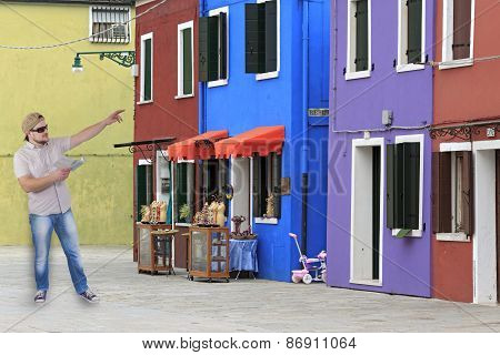 Man with guide book in a hand with houses with coloured facades, Burano, Venice, Itlaly