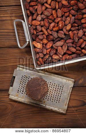 roasted cocoa beans in Vintage heavy cast aluminum roasting pan and and 100% solid chocolate on wood background