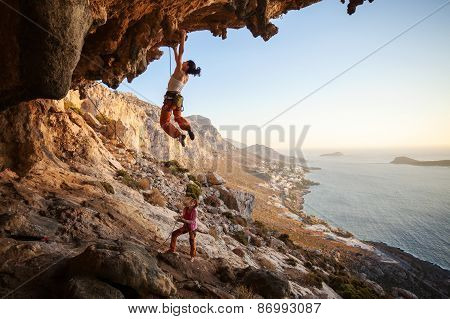 Young woman lead climbing on overhanging cliff