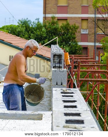 construction worker bricklayer installing red brick with trowel putty knife outdoors