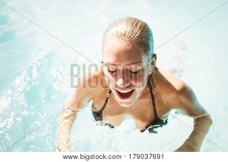 Smiling blonde heading out of water and beathing