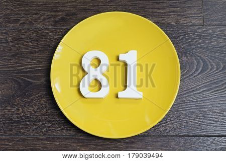 The number eighty-one on the yellow plate and brown background.