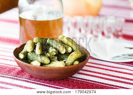 Pickled cucumbers stand on the table behind empty glassware
