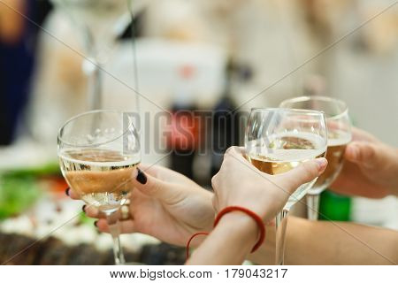 People cheers with glasses full of white wine
