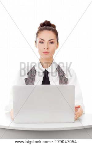 Serious confident businesswoman using laptop computer at office. Attractive woman at work looking at camera against white isolated background