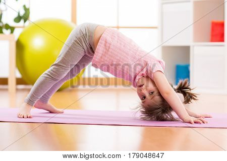 Child preschooler doing fitness exercises on rug at home