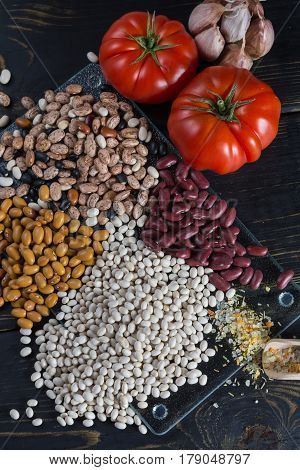 Assortment of beans on black wooden background. Soybean red kidney bean black beanwhite bean red bean and brown pinto beans