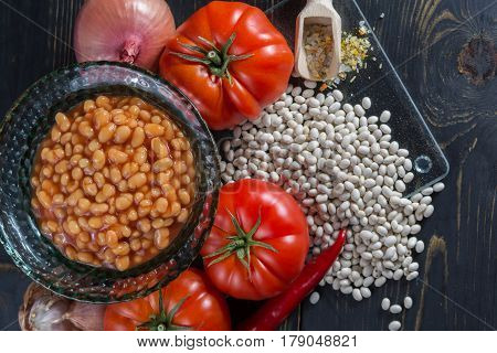 Traditional English food - baked white beans in tomato sauce and ingredients ready to cook - tomatoes dried white beans and onion