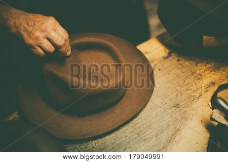 Close up shot of a hatter's hands manufacturing a hat.