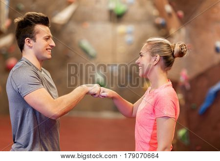 fitness, extreme sport, bouldering, people and healthy lifestyle concept - man and woman exercising at indoor climbing gym making fist bump gesture
