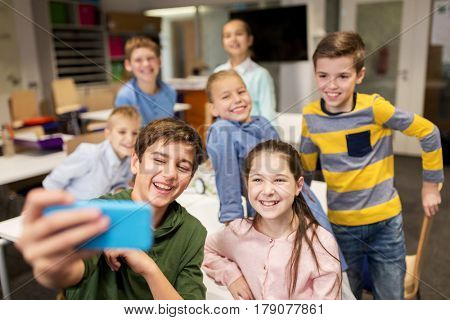 education, elementary school, children and people concept - group of kids taking selfie with smartphone in corridor