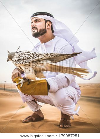 Arabian man walking in the desert at sunrise