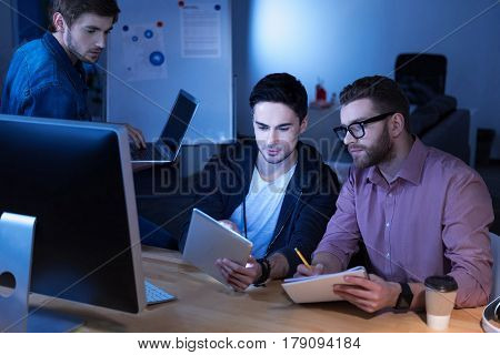 Productive cooperation. Handsome hard working nice programmers doing their tasks and interacting with each other while working in team