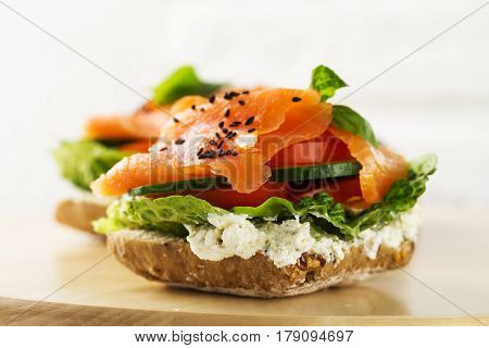 Colorful tasty salted salmon with vegetables on sandwich. Bright background.