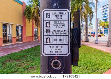 Young man hand pushing button for traffic light. Use traffic lights at the crossroads. Button of the mechanism lights traffic lights on the street. System control traffic light intersection close.