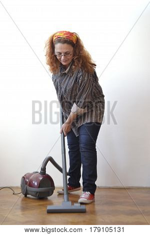 Housewife with vacuum cleaner cleaning floor - front view