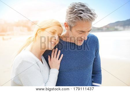 Middle-aged couple walking together on a sandy beach