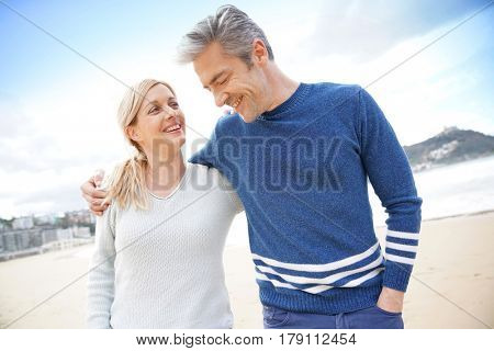 Middle-aged couple walking together on a sandy beach