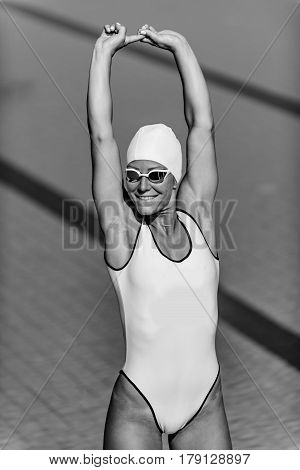 Female swimmer streching on poolside, black and white