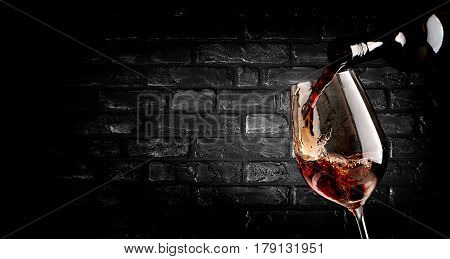 Wine pouring in wineglass near brick wall