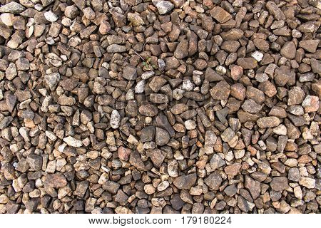 Bulk of granite rubble on the railway. Gray and brown dirty old crushed stone texture or background. A spring cloudy day. Gloomy mood.