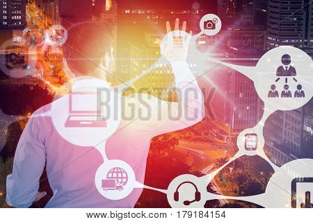 Rear view of businessman pretending to touch invisible screen against illuminated roads by buildings in city 3d