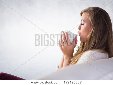 Digital composite of Woman on couch drinking from white mug against white wall