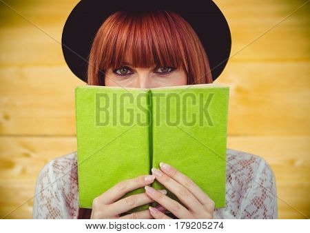 Digital composite of Woman reading against yellow wood panel