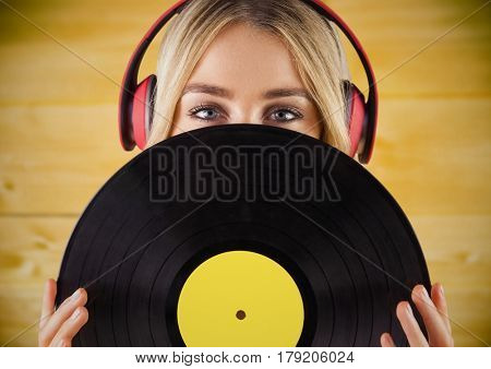 Digital composite of Woman with headphones and record against yellow wood panel