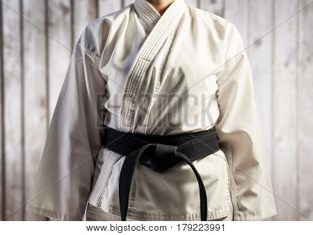 Digital composite of Woman in karate suit mid section against blurry wood panel