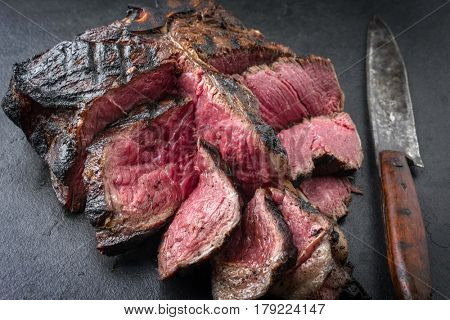 Barbecue dry aged Wagyu Bistecca alla Fiorentina as close-up on a black slate 