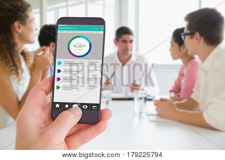 Female hand holding a smartphone against business people discussing in conference meeting