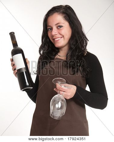Mujer con delantal que presenta una botella de vino con una etiqueta en blanco y un par de gafas