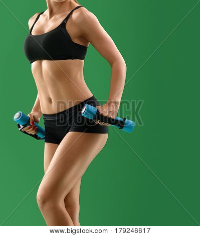 Cropped shot of a female sporty body. Woman with perfect abs exercising with dumbbells. Strong sexy body of a sportswoman gym activity hobby leisure lifestyle strength pumping concept