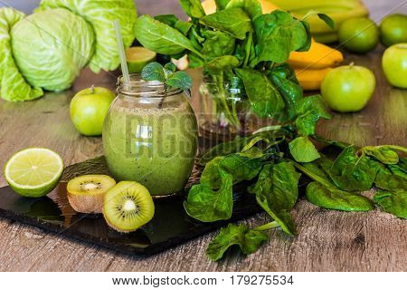 Detox diet. Green smoothie with fruits and vegetables on wooden dark background.