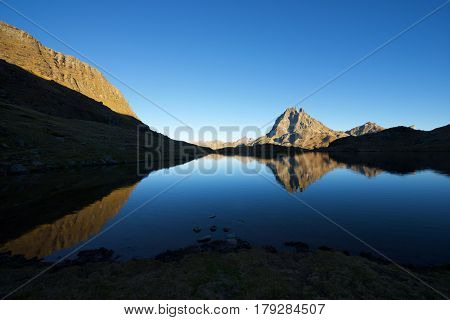 Midi Dossau Peak reflected in Gentau lake. Ossau Valley, Pyrenees National Park, Pyrenees, France.