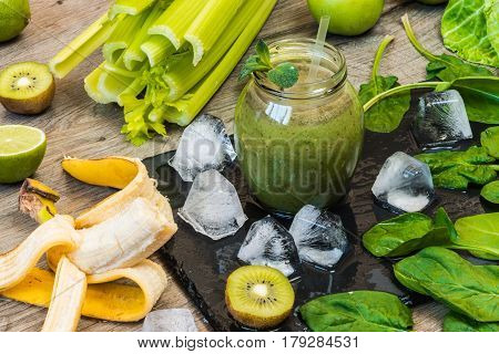 Detox diet. Green smoothie with fruits and vegetables on wooden dark background.