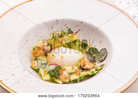 The asparagus with mussels and goose egg sauced ber-blan in a round plate on a table