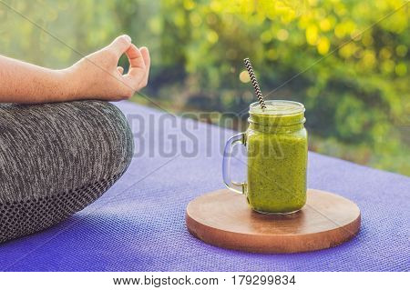 Closeup Of A Woman's Hands During Meditation With A Green Smoothies Of Spinach, Orange And Banana