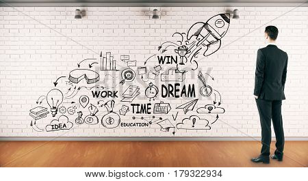 Businessman in brick interior looking at wall with launching rocket sketch. New business concept. 3D Rendering