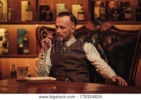 Confident upper class man smoking cigar in gentlemen's club