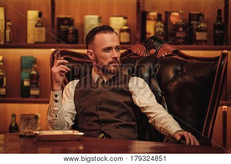 Confident upper class man smoking cigar in gentlemen's club