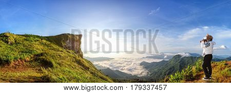 Panorama beautiful landscape nature of sunrise on peak mountain with sun cloud fog bright sky and woman tourist are taking photos in winter at Phu Chi Fa Forest Park Chiang Rai Province Thailand