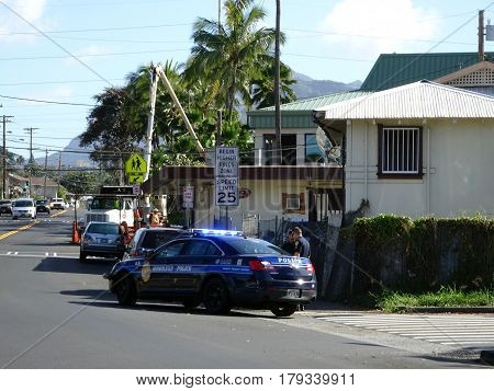 HONOLULU - FEBRUARY 7: Honolulu Police Department police officer pulls over Van on street. The HPD officer is using a white and blue cruiser with lights flashing as he talks to person outside car Hawaii February 7 2017.