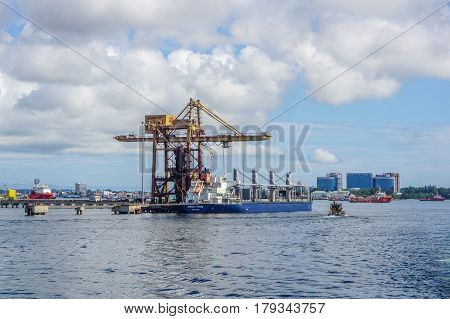 Labuan,Malaysia-Mac 25,2017:A large bulk carrier unloaded iron ore in Antara Steel Mill Plant port at Labuan,Malaysia with background of Labuan town on 23rd Mac 2017.