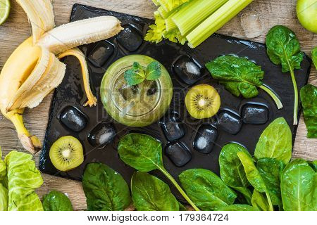Detox diet. Green smoothie with fruits and vegetables on wooden dark background.