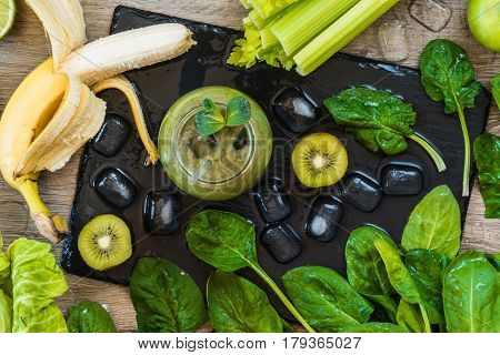 Detox diet. Green smoothie with fruits and vegetables on wooden dark background.