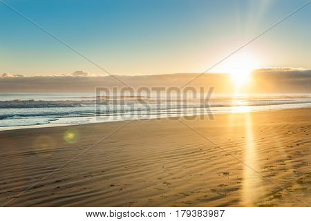 Sunrise over wide flat sandy beach at Ohope Whakatane New Zealand.