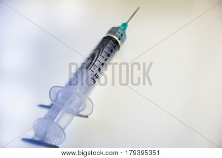 A green tipped syinge containing 2ml of water at a low angle