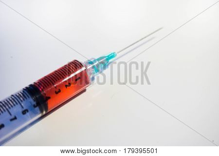 A green tipped syringe containing 4ml of red fluid (blood) from close up